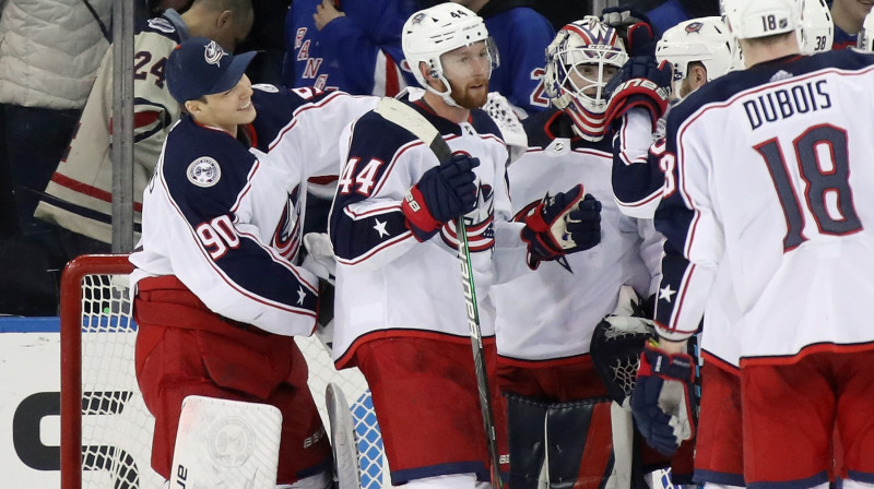 Elvis Merzļikins (pa kreisi) un citi Kolumbusas "Blue Jackets" spēlētāji apsveic Matīsu Kivlenieku (centrā) ar uzvaru NHL debijā. Foto: AFP/Scanpix