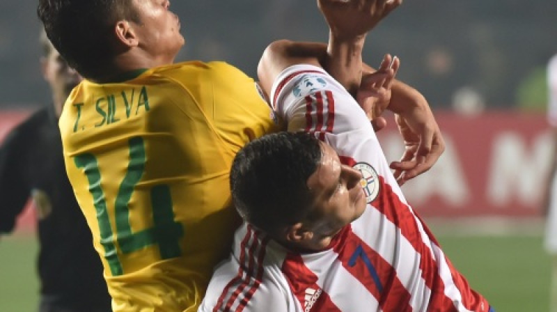 Tjagu Silva cīņā ar paragvajiešu uzbrucēju Raulu Bobadilju
Foto: AFP/Scanpix