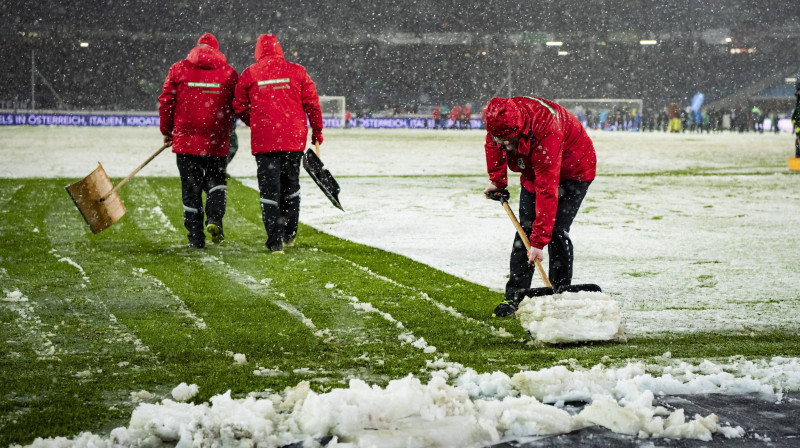 Strādnieki attīra laukumu no sniega Vācijas Bundeslīgas spēlē. Foto: www.imago-images.de/Scanpix