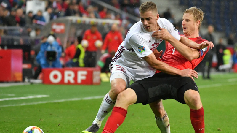 Latvijas izlases uzbrucējs Vladislavs Gutkovskis cīņā ar Austrijas valstsvienības aizsargu Martinu Hinteregeru. Foto: AFP/Scanpix