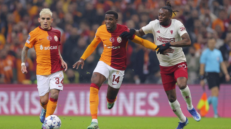 Stambulas "Galatasaray" futbolisti Lukass Torreira (Nr. 34) un Vilfrīds Zahā (Nr. 14) pret Mančestras "United" aizsargu Āronu Van-Bisaku. Foto: AP/Scanpix