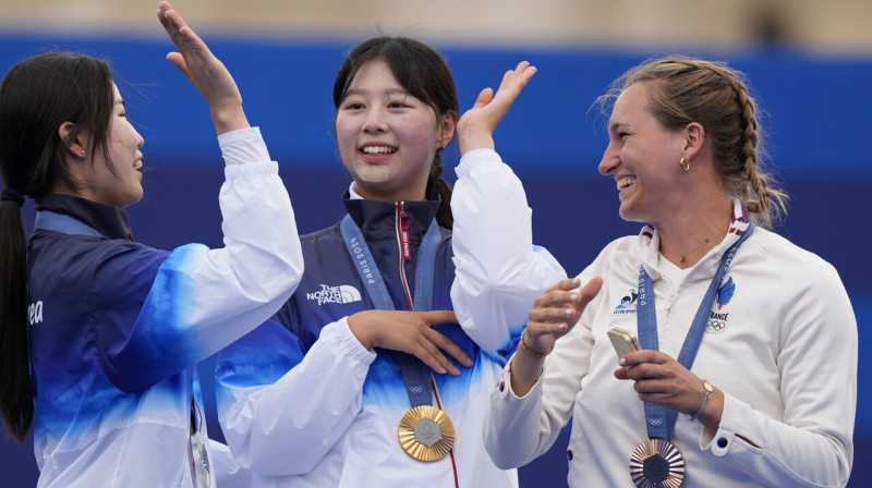 No kreisās: Dienvidkorejas loka šāvējas Sūhjona Nama un Sīhjona Lima, kā arī Francijas sportiste Liza Barbelāna pēc individuālajām sacensībām.
Foto: Brynn Anderson/AP/Scanpix