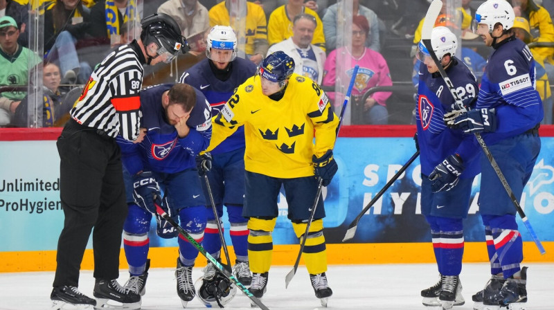Zviedru uzbrucējs Jespers Fredēns apvaicājas par franču aizsarga Kevina Spinoci veselību. Foto: André Ringuette/IIHF