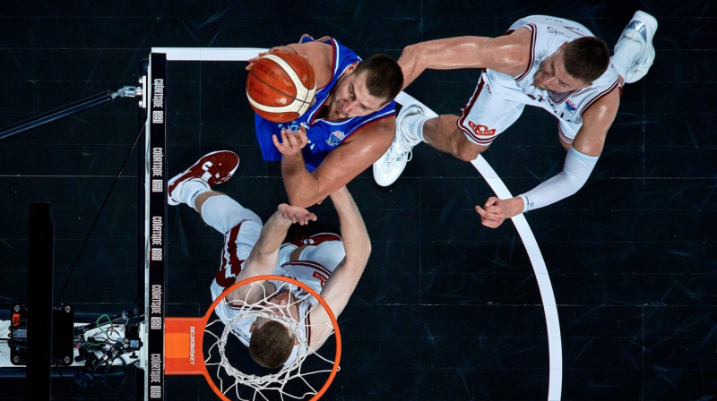 Nikola Jokičs un Kristaps Porziņģis cīņā groza tuvumā. Foto: FIBA