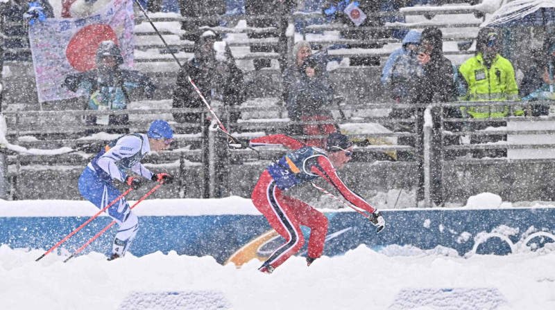 Norvēģis Jenss Luross Oftebro un soms Ēro Hirvonens finišā komandu sacensībās ziemeļu divcīņā. Foto: Javier Soriano/AFP/Scanpix