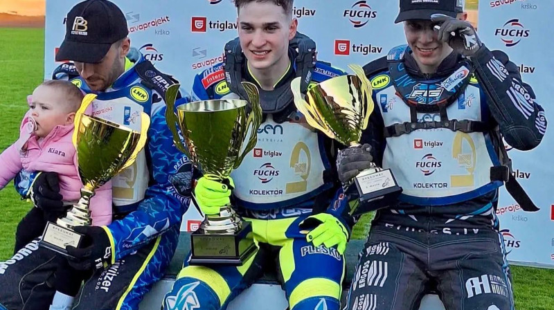 Francis Gusts (pa labi) uz goda pjedestāla Krško.