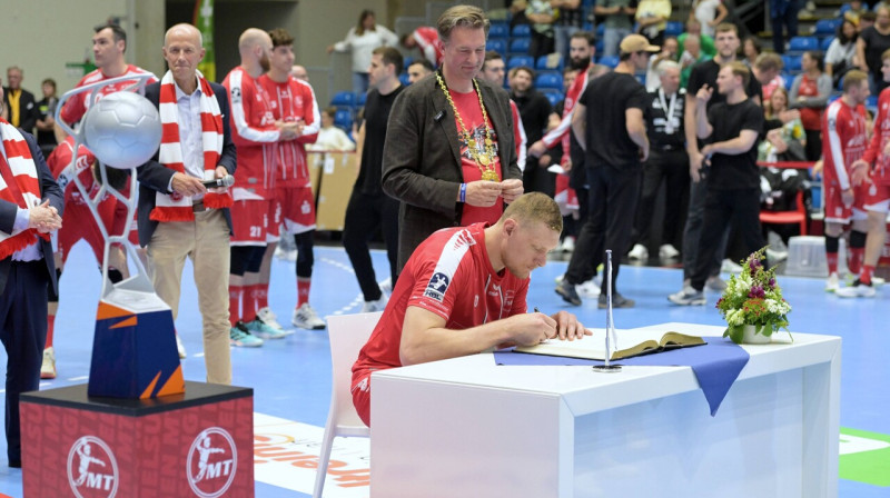 Dainis Krištopāns veic ierakstu Melzungenes kluba zelta grāmatā, blakus EHF Eiropas līgas trofeja. Foto: Roland Sippel/Eibner-Pressefoto/Scanpix